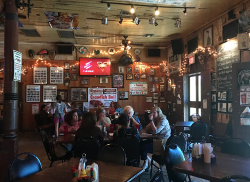 A lively restaurant interior with wooden decor, patrons dining, and walls adorned with photos and memorabilia.