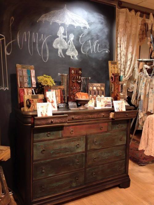A vintage dresser displays jewelry and accessories against a chalkboard backdrop with "Jenny & Eva" written on it.