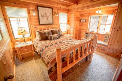 Cozy wooden bedroom with a log bed, rustic decor, and large windows letting in natural light.