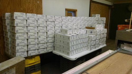 A large stack of neatly organized boxes in a warehouse setting, with wooden walls and a table in the foreground.