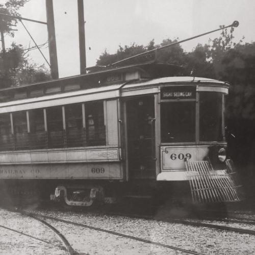 A vintage streetcar labeled "609" with a sign reading "Sight Seeing Car," parked on a railway track.