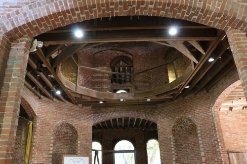 Interior view of a brick building featuring exposed wooden beams and modern lighting.