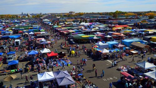 Aerial view of a bustling outdoor market with colorful tents and crowds of people shopping.