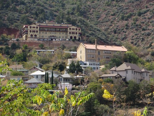 Historic buildings nestled in a hillside landscape, surrounded by greenery and mountains.