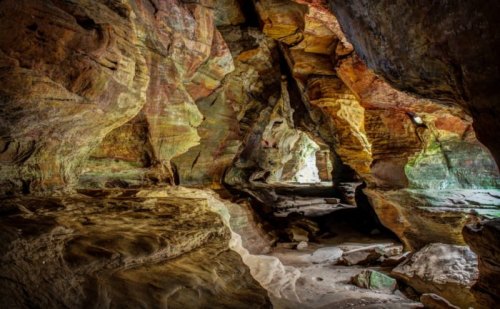 A colorful cave interior with textured rock formations and soft lighting illuminating the passageways.