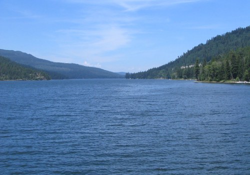 A serene lake surrounded by lush green mountains under a clear blue sky.