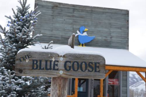 A wooden sign reading "The Blue Goose" in front of a snowy building with a blue duck decoration.