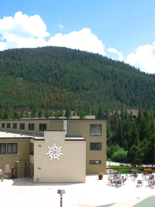 A modern building with a decorative star design, surrounded by lush green mountains and a clear blue sky.