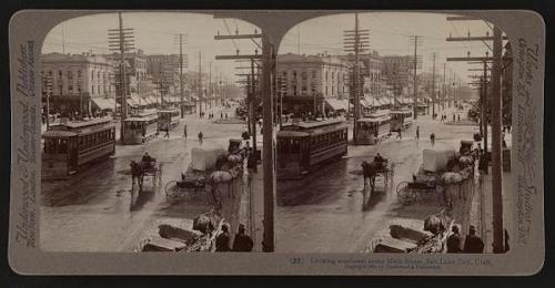 Historic street scene in Salt Lake City, featuring horse-drawn carriages and early electric streetcars.