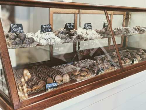 A display case filled with various chocolate truffles and treats, labeled with small signs.
