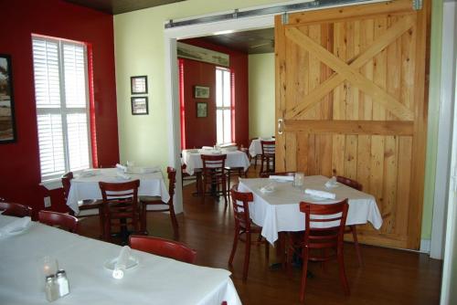 Cozy restaurant interior with wooden tables, chairs, and a large sliding barn door. Warm red and green walls.