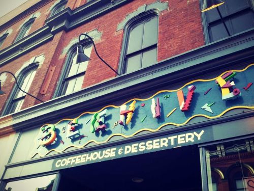 Colorful sign for "Beetlejuice Coffeehouse & Dessertery" on a brick building with decorative elements.