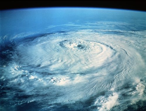 Aerial view of a large hurricane swirling over the ocean, showcasing its circular cloud formation and atmospheric patterns.