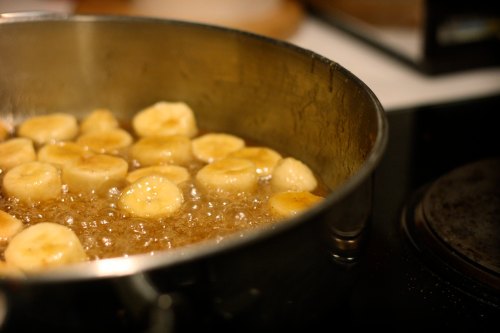 Sliced bananas frying in a pan, bubbling in hot oil, creating a golden-brown color.
