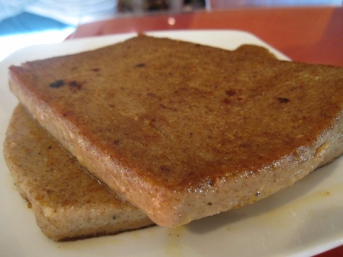 Two golden-brown slices of cooked flatbread on a white plate, with a slightly crispy surface.