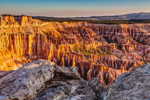 A stunning view of Bryce Canyon's colorful rock formations at sunset, with layered cliffs and a clear sky.