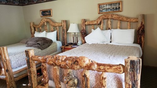 Cozy room with two rustic wooden beds, a lamp, and a nightstand, featuring natural wood accents and soft bedding.