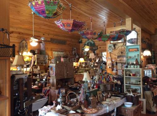 A cozy shop filled with vintage items, colorful umbrellas hanging from the ceiling, and various decorative pieces.