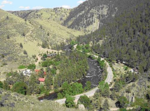 A scenic view of a winding river surrounded by lush greenery and mountains under a clear blue sky.