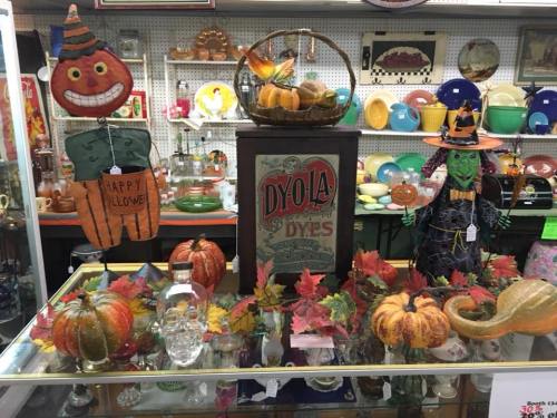 A display of vintage Halloween decorations, including pumpkins, a witch, and colorful autumn leaves.