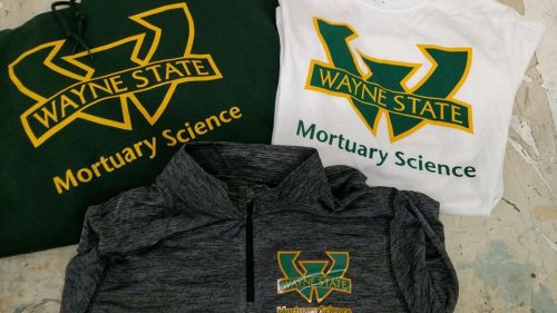 Three Wayne State University apparel items featuring "Mortuary Science" in green and yellow on a dark gray background.