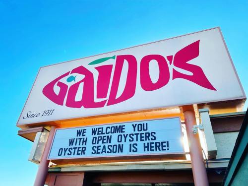 Sign for Gaido's restaurant, welcoming guests to oyster season with a bright blue sky in the background.