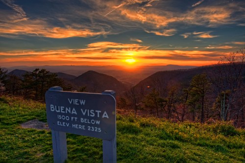 Sunset over mountains with a sign reading "View Buena Vista, 1500 ft. below, Elev. here 2325."