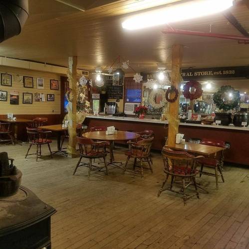 Cozy interior of a rustic bar with wooden tables, chairs, and festive decorations, featuring a warm, inviting atmosphere.