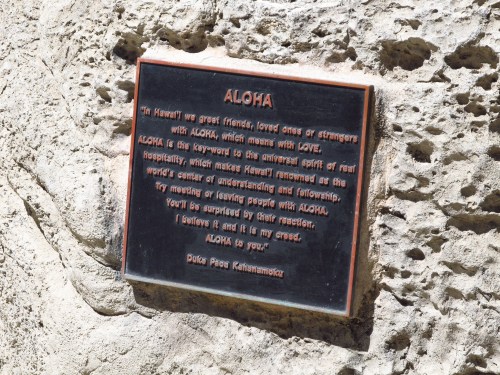 Plaque on a rock that reads "Aloha" with a message about friendship, love, and understanding in Hawaiian culture.