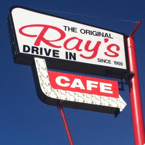 Sign for Ray's Drive-In Cafe, established in 1959, featuring bold red and white lettering against a blue sky.