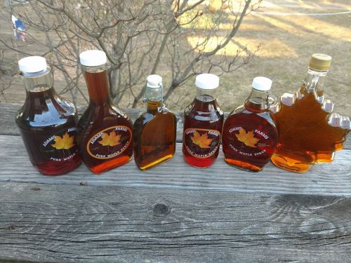 A variety of maple syrup bottles in different shapes and sizes displayed on a wooden surface.