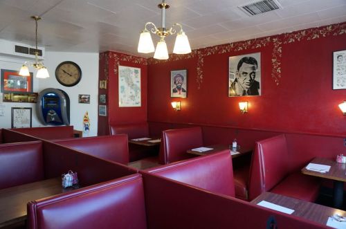 Cozy diner interior with red walls, booth seating, vintage decor, and warm lighting.