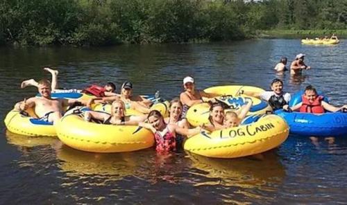 A group of people enjoying a sunny day floating on yellow inner tubes in a river.