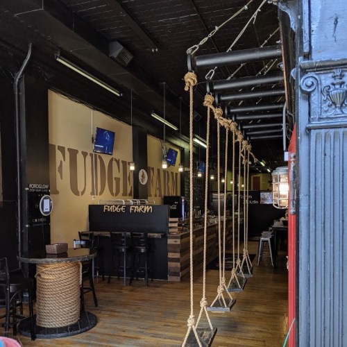 Interior of Fudge Farm with wooden swings, a bar area, and a warm, inviting atmosphere.