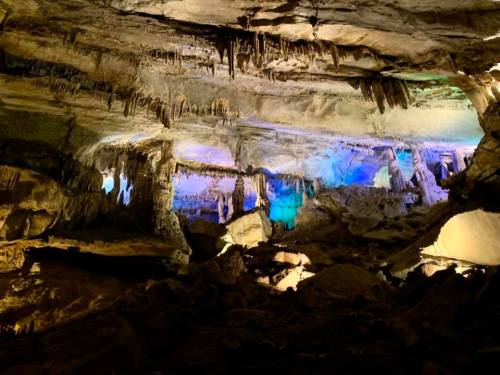 A stunning cave interior with stalactites and stalagmites, illuminated by colorful lights.