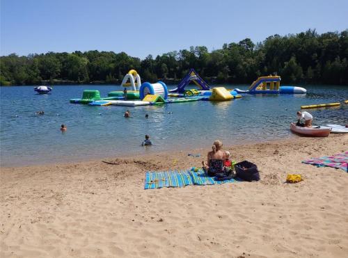 A sandy beach with people swimming and a colorful inflatable water park in the background on a sunny day.