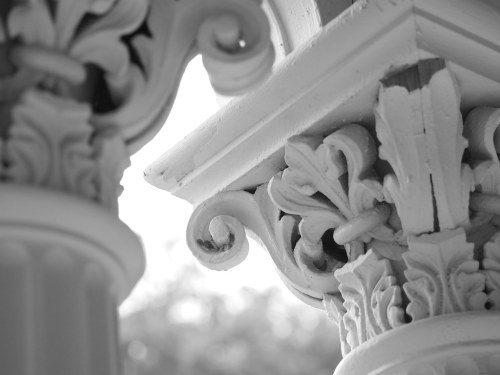 Close-up of intricately carved white architectural columns with decorative scrolls and floral motifs.