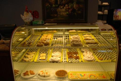 A display case filled with various baked goods, including donuts, cookies, and pastries, in a bakery setting.