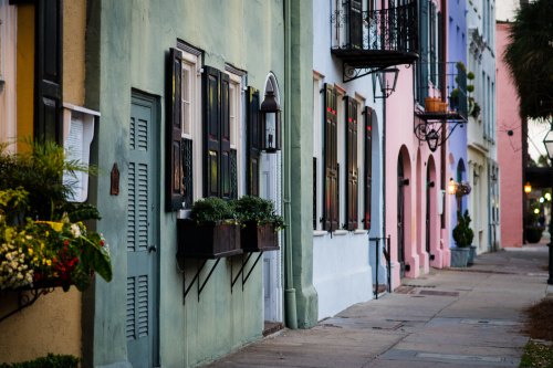 Colorful historic buildings line a charming street, adorned with window boxes and decorative balconies.