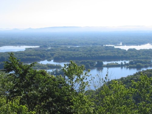 A scenic view of a river winding through lush green landscapes under a clear blue sky.