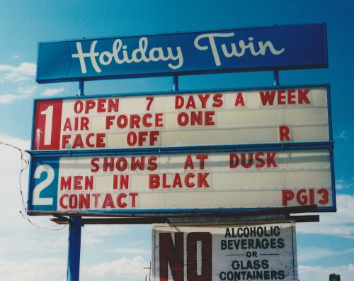 Sign for Holiday Twin featuring movie listings: "Air Force One" and "Men in Black," open 7 days a week.