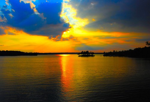 A vibrant sunset over a calm lake, with colorful clouds reflecting on the water's surface.