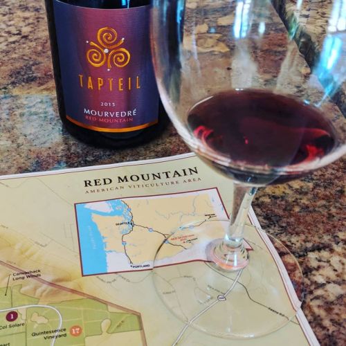 A glass of red wine beside a bottle labeled "Tapteil Mourvèdre 2015" and a map of the Red Mountain viticulture area.