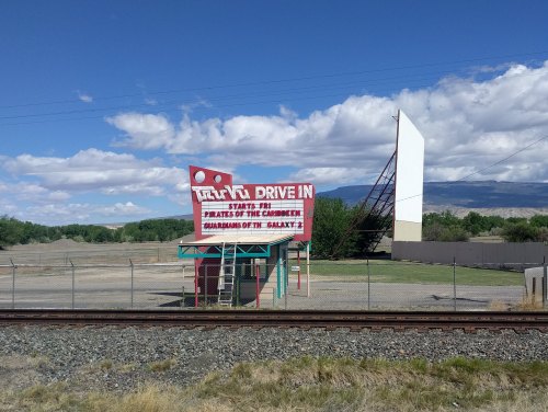 A vintage drive-in theater sign advertising "Pirates of the Caribbean" with a large empty screen in the background.