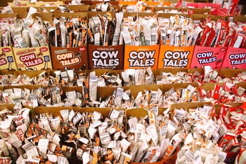 A colorful display of various Cow Tales candy boxes, filled with individually wrapped treats in multiple flavors.