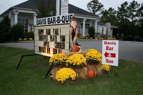 Sign for Davis Bar-B-Que with fall decorations, announcing "Happy Fall Y'all," and featuring apple cobbler and special plates.
