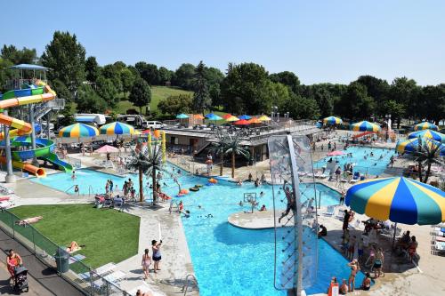 A busy water park with colorful slides, umbrellas, and people enjoying the pool on a sunny day.