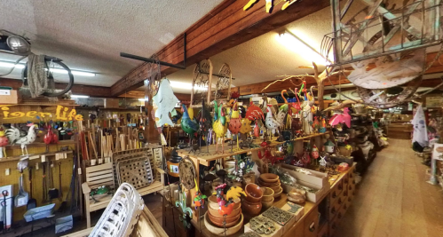 A vibrant shop filled with colorful decorations, crafts, and various wooden items displayed on shelves and tables.