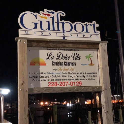 Sign for "La Dolce Vita Cruising Charters" in Gulfport, Mississippi, offering yacht cruises and dolphin watching.