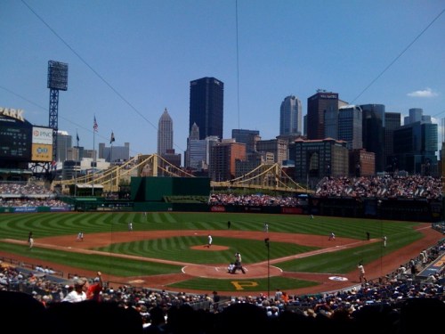 A baseball game at PNC Park in Pittsburgh, with the city skyline and yellow bridges in the background.